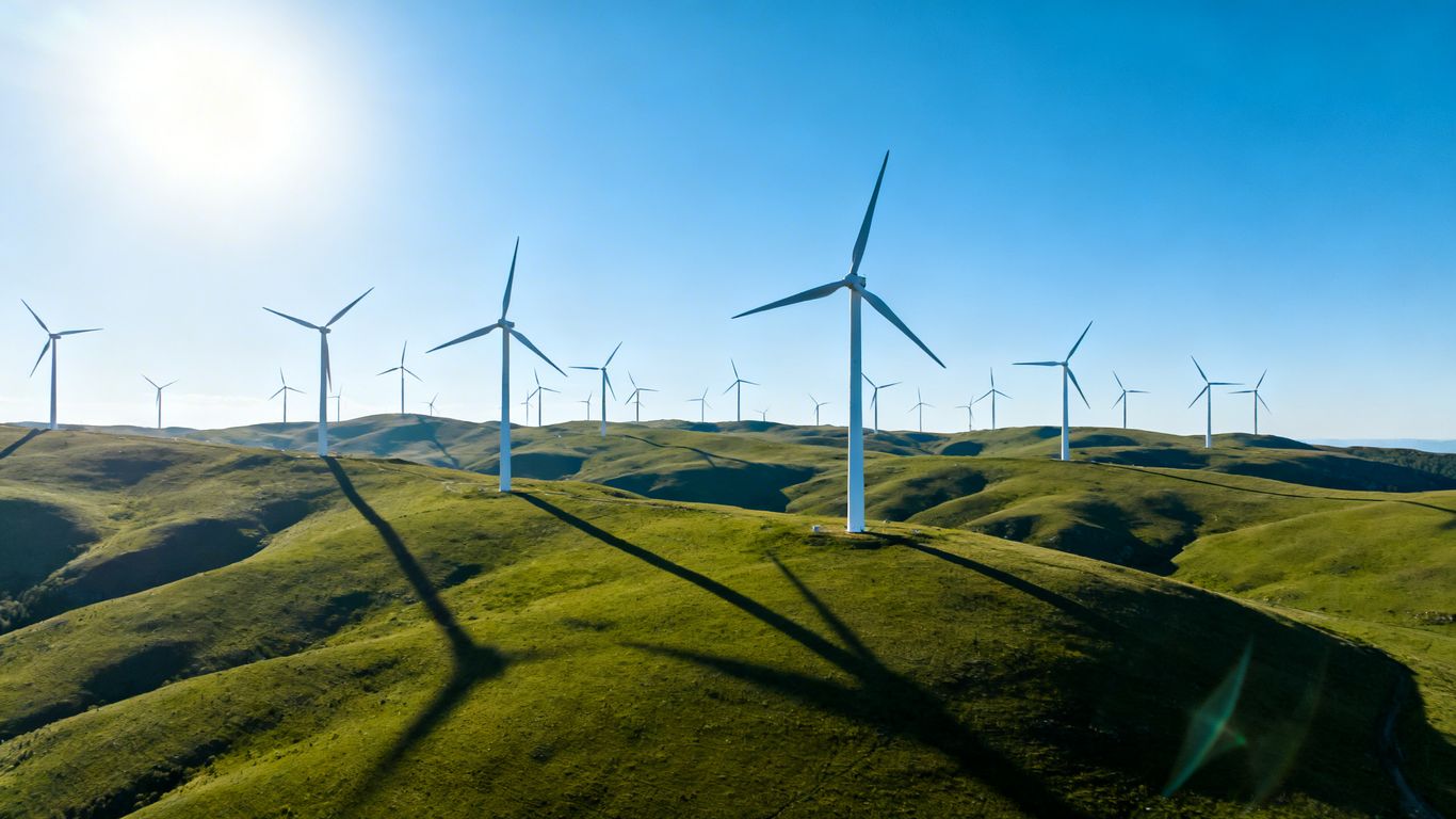 Éoliennes sur fond de ciel bleu et de collines vertes.